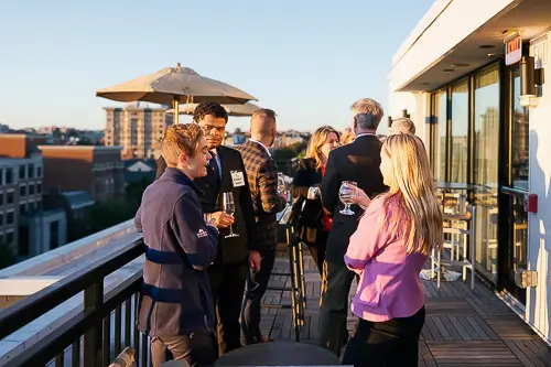 Corporate event photography Washington DC capturing a rooftop networking reception at sunset