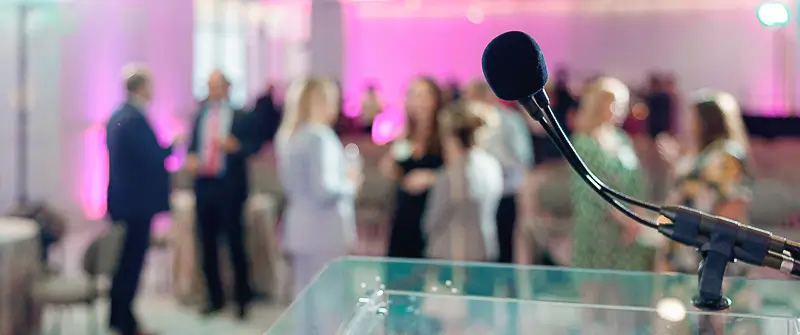 Microphone on a stage at a corporate event in Washington DC with guests networking in the background