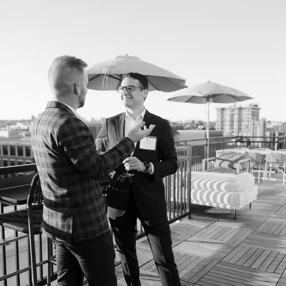 Black and white photo of two guests in conversation during a Washington DC rooftop networking event