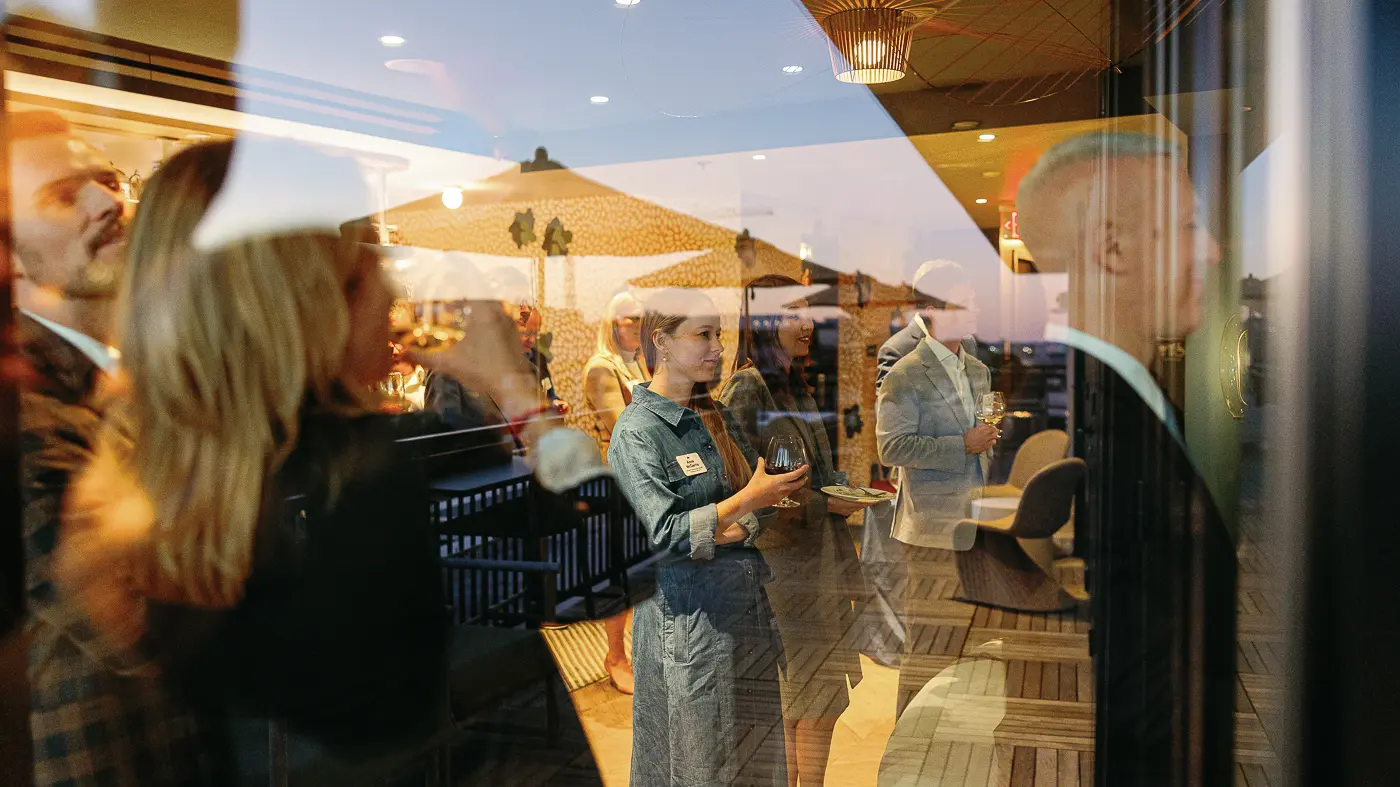 Warm candid reception moment photographed through glass during a Washington DC rooftop corporate event