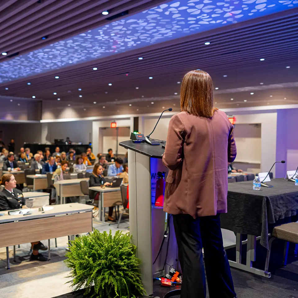Featured presenter walking toward the FDA-PDA Annual Conference stage in front of a seated audience