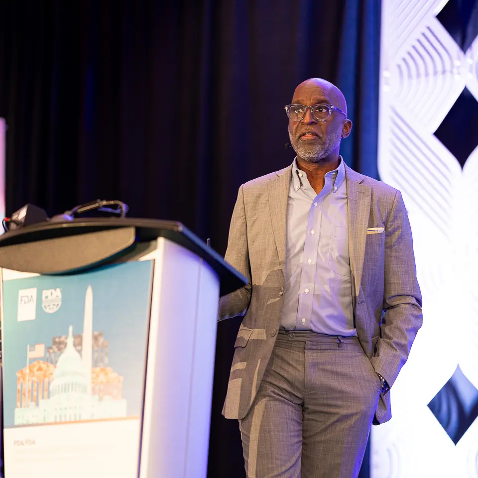 Male speaker presenting at the FDA-PDA Annual Conference podium beside stage lighting
