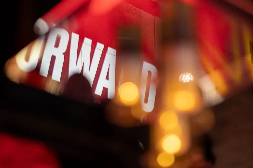 Close-up of blurred Forward campaign branding with warm event lights in the background
