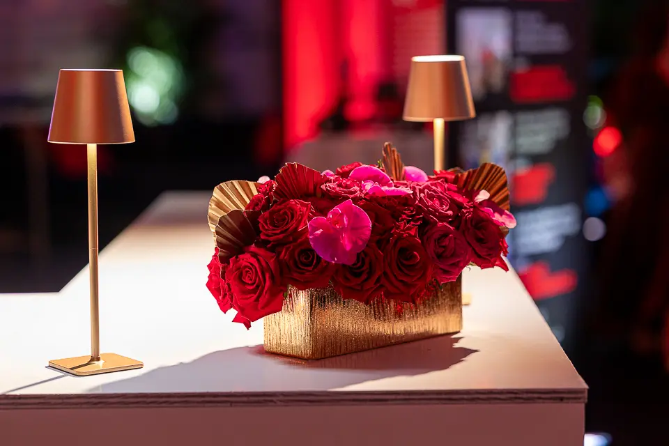 Red floral arrangement and small table lamps on a white reception counter at the University of Maryland Forward event