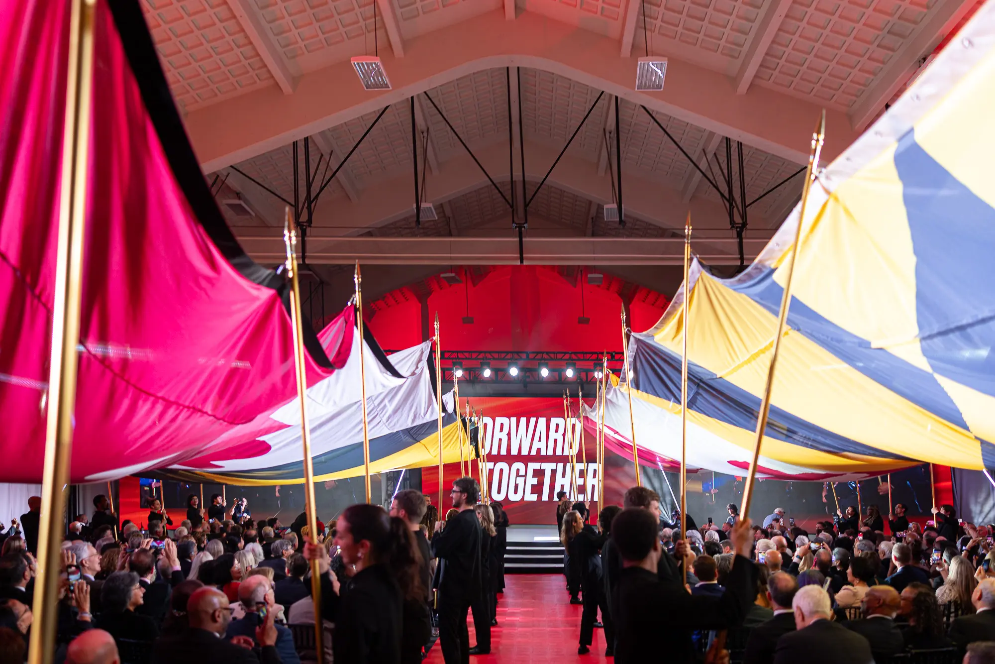 University of Maryland Forward Together program with large campaign flags and seated audience inside the event venue