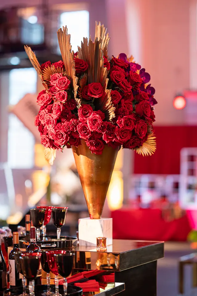 Red floral centerpiece with cocktail glasses at the University of Maryland Forward fundraising campaign event