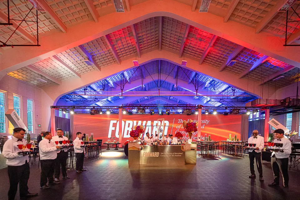 Wide University of Maryland Forward reception space with campaign stage, lounge seating, and illuminated ceiling
