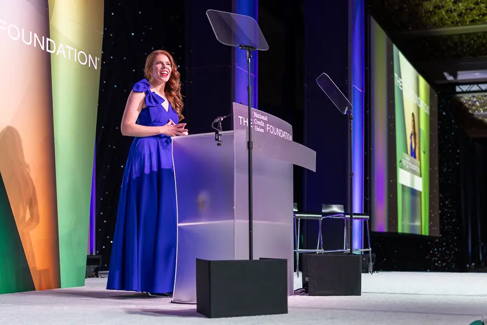 Woman in a blue evening gown speaking at the Herb Wegner Awards 2026 podium.