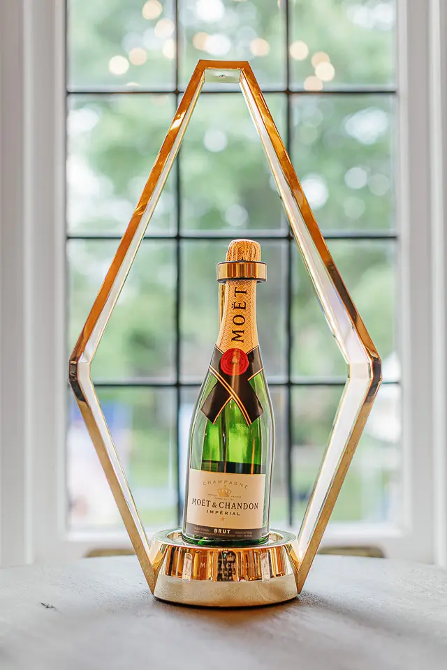 Champagne bottle presented in a geometric gold display stand
