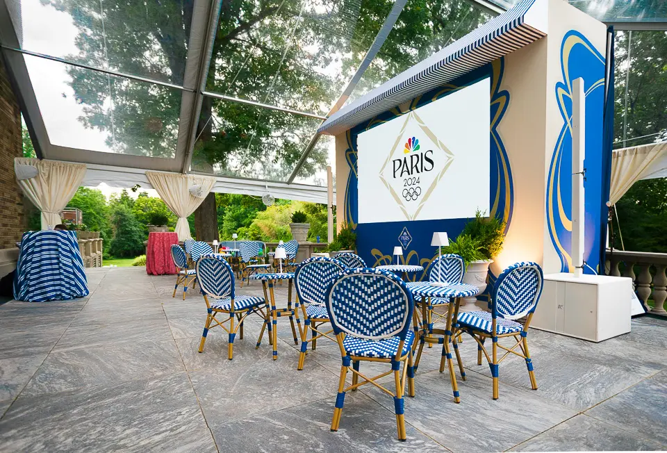 Garden patio seating with blue chairs, umbrellas, and event signage