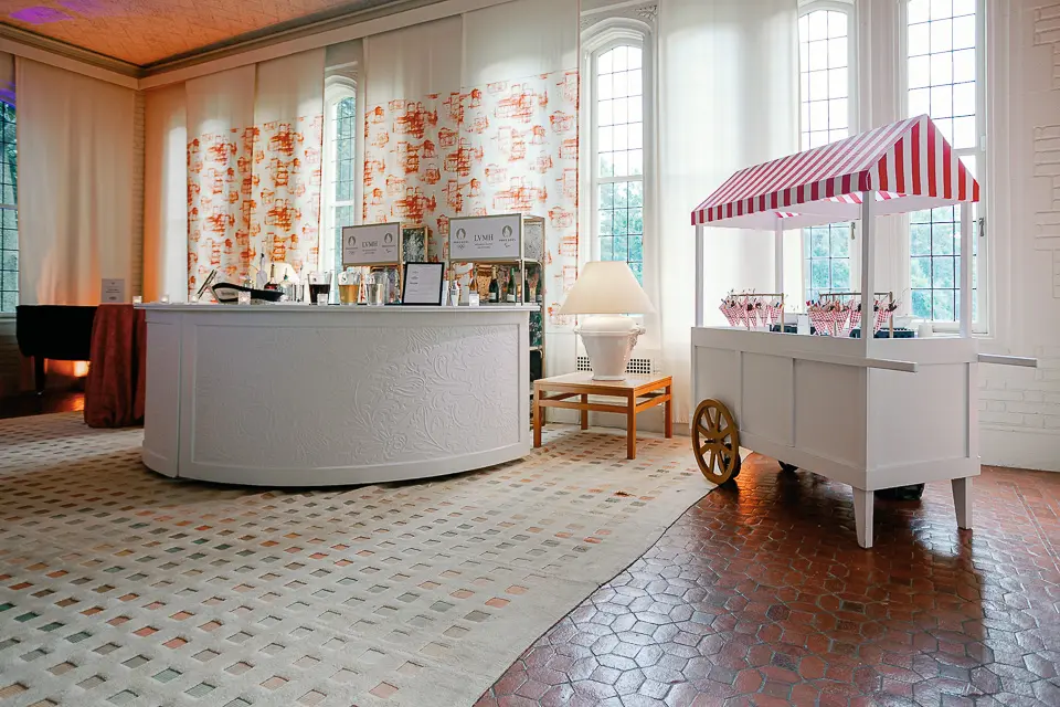 Striped hospitality cart and floral wall in a bright event room