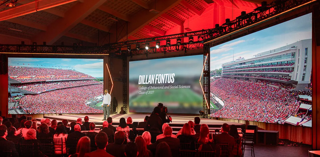 Corporate event photographer Washington DC capturing large-scale stage production with LED screens and keynote presentation at University of Maryland fundraising event.